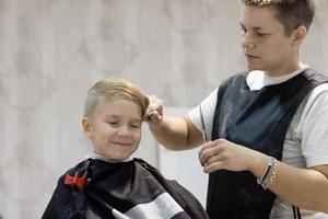 garçon heureux ayant une coupe de cheveux au salon de coiffure. photo