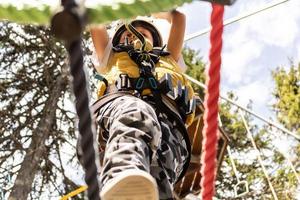 ci-dessous, vue d'un enfant marchant sur une tyrolienne et franchissant les obstacles lors d'une visite de la canopée. photo