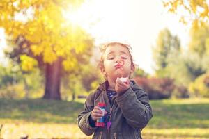 petite fille soufflant des bulles de savon dans le parc. photo