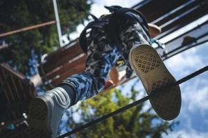 ci-dessous la vue d'un enfant marchant sur une corde suspendue dans un parc d'aventure. photo