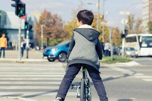 petit garçon à vélo attendant les feux de circulation sur le passage clouté. photo