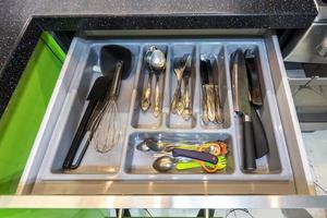 ensemble d'assiettes, tasses, couteaux, fourchettes et verres à vin sur l'étagère de l'armoire de cuisine photo