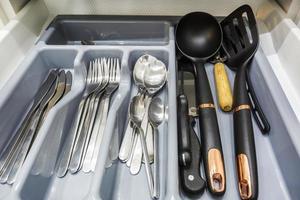 ensemble de couteaux, fourchettes et cuillères sur l'étagère de l'armoire de cuisine photo