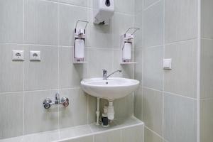coude distributeur de savon et d'antiseptique ou désinfectant mural pour la désinfection des mains et robinet d'eau évier avec robinet salle de bain ou clinique photo