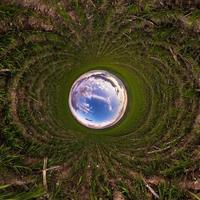 boule de ciel bleu au milieu d'une route ou d'un champ d'asphalte tourbillonnant. inversion de minuscule planète transformation de panorama sphérique à 360 degrés. vue abstraite sphérique. courbure de l'espace. photo