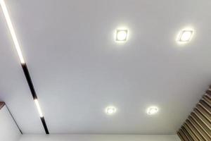 plafond suspendu avec lampes halogènes et construction de cloisons sèches dans une pièce vide d'un appartement ou d'une maison. plafond tendu de forme blanche et complexe. photo