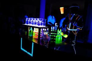 barman professionnel et spectacle de lumière led. silhouette de barman moderne secouant la boisson au bar à cocktails de nuit. photo