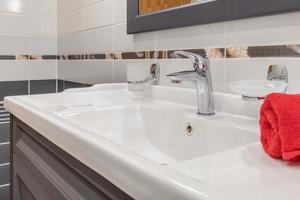 lavabo en métal avec robinet dans une salle de bain chère. détail d'une toilette d'angle avec douchette murale photo