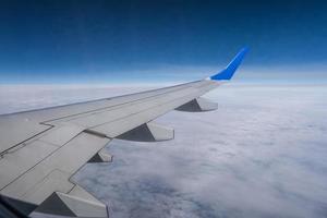 aile d'avion depuis la fenêtre de l'avion avec vue sur le ciel bleu et les beaux nuages photo