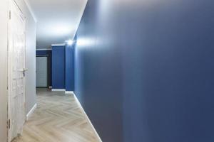 couloir vide non meublé avec des réparations préparatoires minimales avec moulures. intérieur de murs blancs et bleus photo
