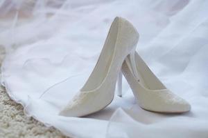 chaussures de mariage blanches sur le voile de la robe blanche de la mariée photo
