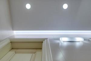 plafond suspendu avec lampes halogènes et construction de cloisons sèches dans une pièce vide d'un appartement, d'un appartement, d'un bureau, d'une clinique, d'un hôtel ou d'une maison. plafond tendu de forme blanche et complexe. photo