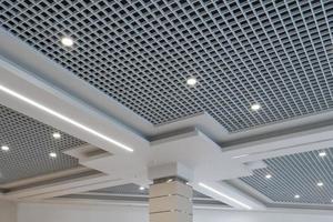 plafond suspendu et grillagé avec lampes halogènes et construction de cloisons sèches dans une pièce vide du magasin ou de la maison. plafond tendu de forme blanche et complexe. photo