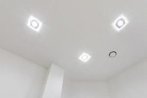plafond suspendu avec lampes halogènes et construction de cloisons sèches dans une pièce vide d'un appartement ou d'une maison. plafond tendu de forme blanche et complexe. photo