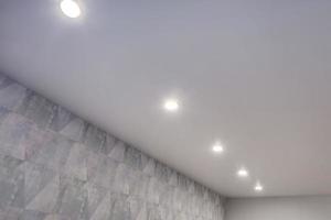 plafond suspendu avec lampes halogènes et construction de cloisons sèches dans une pièce vide d'un appartement ou d'une maison. plafond tendu de forme blanche et complexe. photo