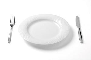 assiette vide avec couteau et fourchette isolé sur fond blanc. photo