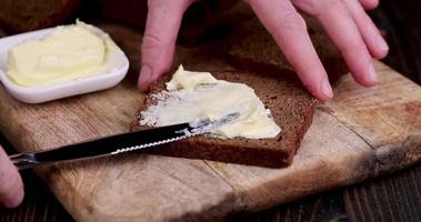 étaler du beurre de lait sur du pain de seigle noir photo