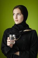 femme du moyen-orient en abaya tenant un verre d'eau photo