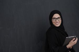 jeune femme d'affaires arabe en vêtements traditionnels ou abaya tenant une tablette photo