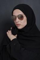 jeune femme d'affaires musulmane en vêtements traditionnels ou abaya et lunettes de soleil posant devant un tableau noir photo