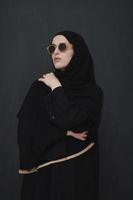 jeune musulman en vêtements traditionnels ou abaya et lunettes de soleil posant devant un tableau noir photo