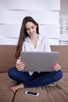 jeune femme détendue à la maison travaillant sur un ordinateur portable photo