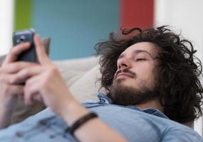 jeune homme utilisant un téléphone portable à la maison photo