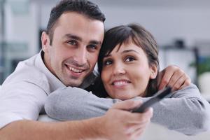 jeune couple détendu devant la télé à la maison photo