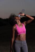 femme afro-américaine buvant de l'eau après avoir fait du jogging dans la nature photo