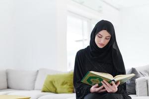 jeune femme musulmane lisant le coran à la maison photo