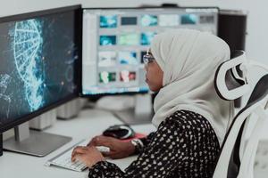 jeune femme d'affaires musulmane moderne afro-américaine portant un foulard dans un lieu de travail créatif et lumineux avec un grand écran. photo