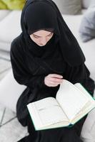 jeune femme musulmane lisant le coran à la maison photo