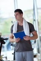 entraîneur avec presse-papiers debout dans une salle de sport lumineuse photo