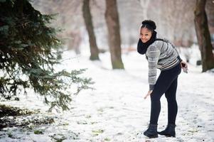 femme africaine portant une écharpe noire pose en journée d'hiver en europe avec un téléphone portable à portée de main. photo