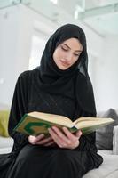 portrait de jeune femme musulmane lisant le coran dans une maison moderne photo