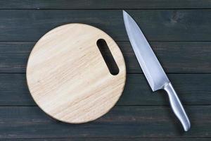 couteau de cuisine en gros plan et planche à découper ronde en bois