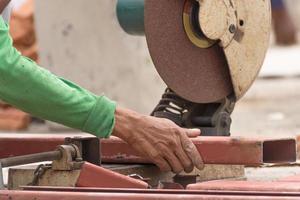 Travailleur coupant du métal avec une meuleuse sur un chantier de construction photo