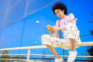 femme noire surfant sur un téléphone portable sur une balustrade photo