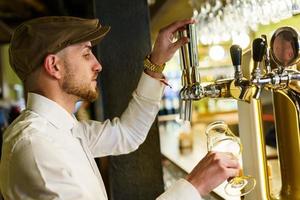 barman mâle versant de la bière dans un beau pub photo