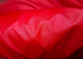 grosses gouttes d'eau sur un textile rouge à effet imperméable. imprégnation hydrofuge. gouttes de texture sur le tissu photo