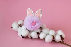 belles fleurs de coton blanc et un petit lapin pelucheux lilas sur fond rose. notion de pâques photo