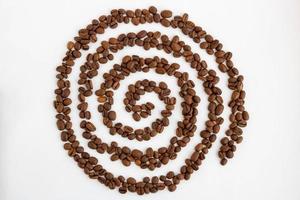 les grains de café sont disposés sur un fond blanc sous la forme d'une spirale photo