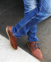 homme portant un jean bleu avec des chaussures en cuir marron. photo