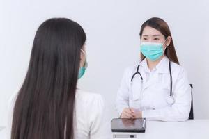 une patiente asiatique consulte son médecin sur sa santé, le médecin lui donne des conseils tandis que les deux portent un masque médical pour protéger les maladies infectieuses à l'hôpital. photo