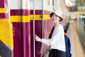 une belle femme asiatique marchait dans le train pour voyager pendant que le train était garé sur le quai. photo