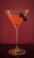 un grand verre élégant avec un cocktail rouge et le fond rouge photo