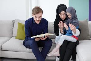 famille musulmane lisant le coran et priant à la maison photo