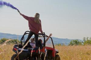 des gens excités s'amusant en profitant d'une belle journée ensoleillée tenant des torches colorées tout en conduisant une voiture buggy hors route photo