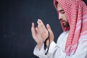 homme arabe faisant la prière traditionnelle à dieu, garde les mains dans le geste de prière devant le tableau noir photo