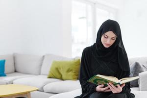 jeune femme musulmane lisant le coran à la maison photo